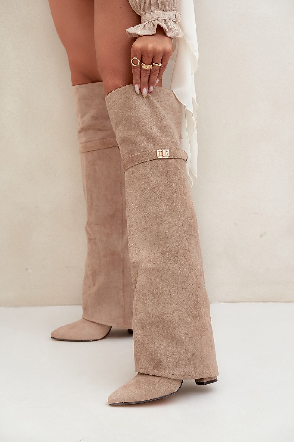 Beige dameslaarzen van imitatiesuède met omgeslagen schacht en goudkleurig detail – elegante laarzen met puntige neus en lage hak.