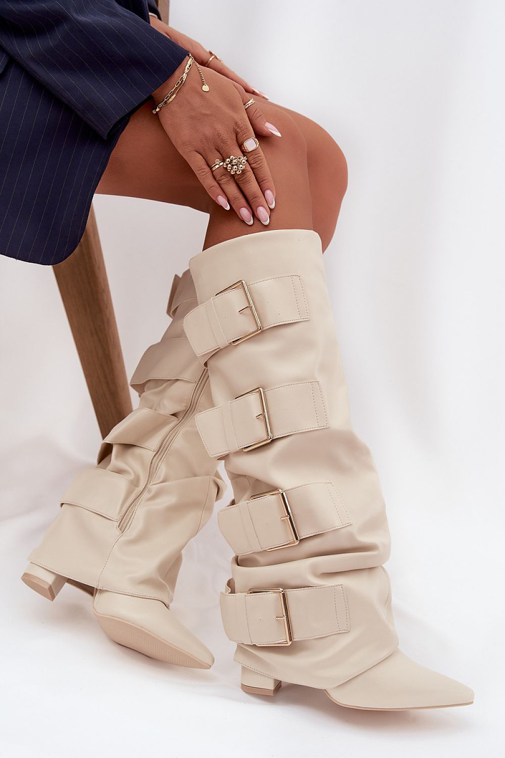 Beige dameslaarzen van imitatieleer met vier gespen en spitse neus – stijlvolle laarzen met blokhak en moderne afwerking.
