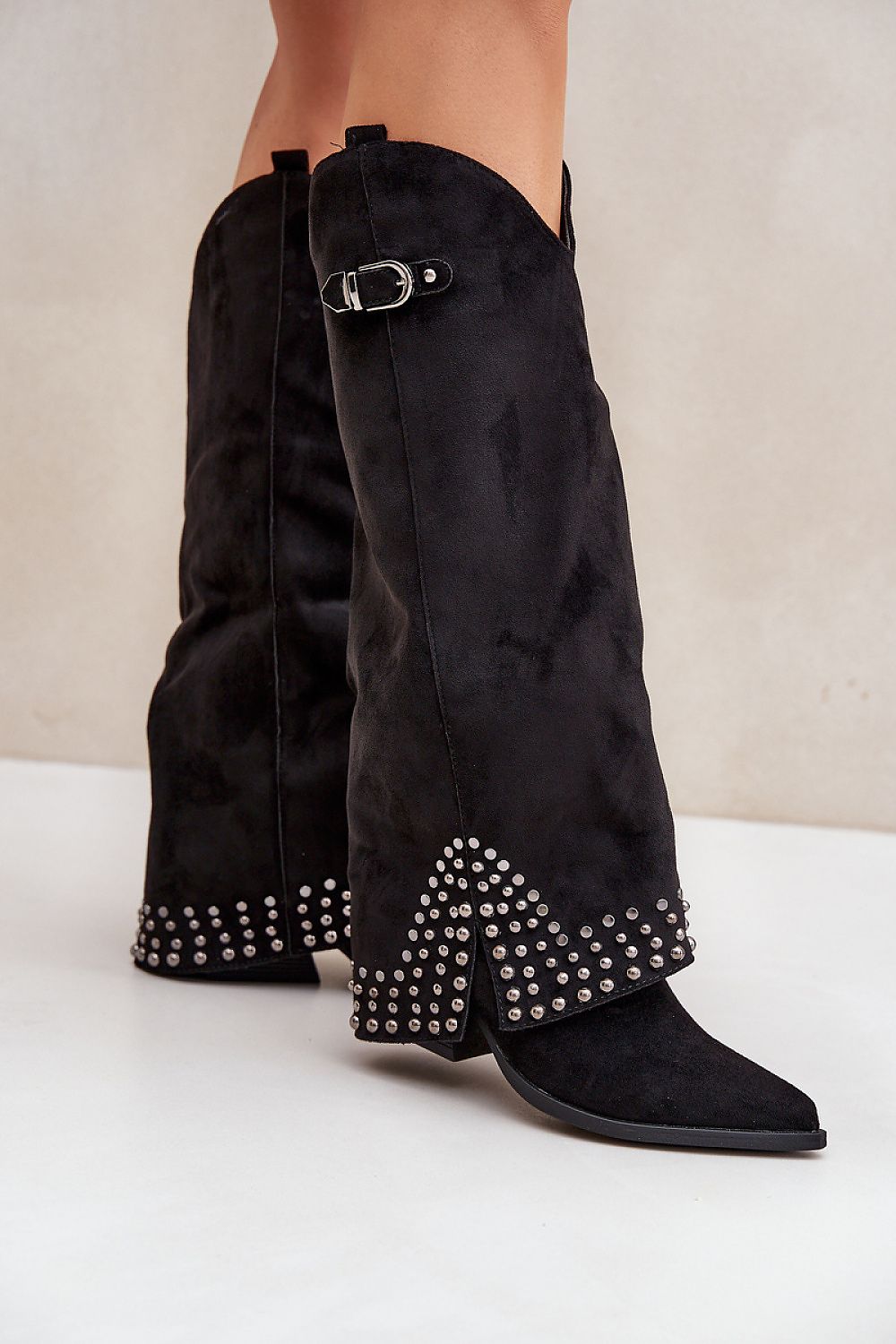 Elegante zwarte suède laarzen met omgeslagen schacht, studs en gespdetail – trendy dameslaarzen in westernstijl met puntige neus en lage hak.